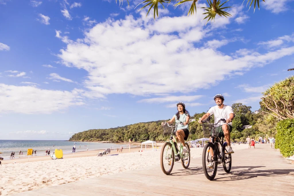 Bike riders with rental bikes on Noosa main beach boardwalk
